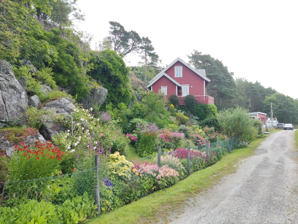 A very neat and pretty garden belinging to a neat red house.